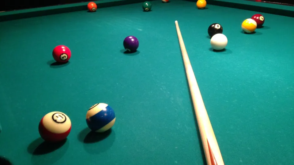 Billardkugeln und Queue auf einer grünen Spielfläche