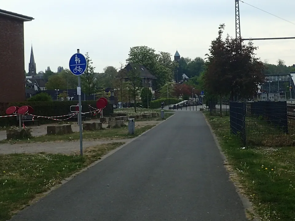 Radweg mit blauem Verkehrsschild am Stadtrand
