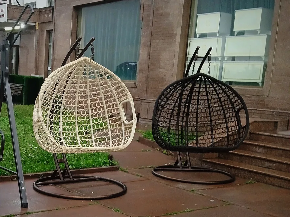 Zwei Hängesessel aus Rattan mit Gestell auf einer Terrasse