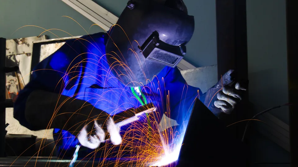 Schweißarbeit an einem Werkstück, der Lichtbogen wirft sichtbare Funken