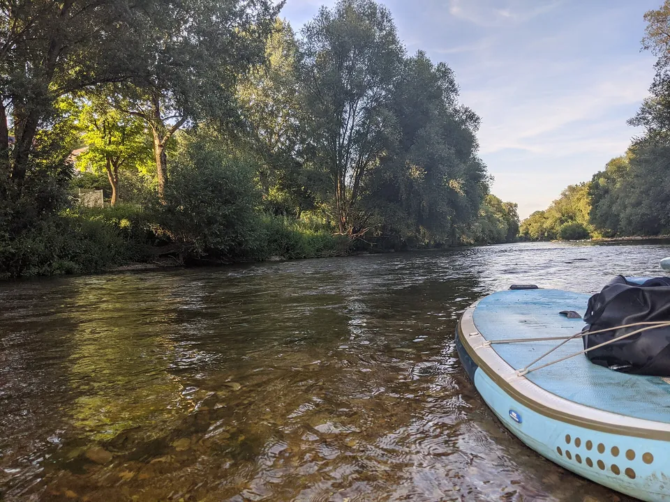 Ein SUP-Board liegt an einer Kiesbank im Fluss
