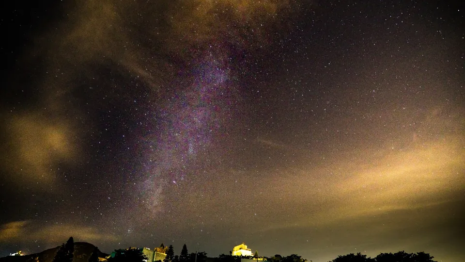 Sternenhimmel über einer beleuchteten Stadt